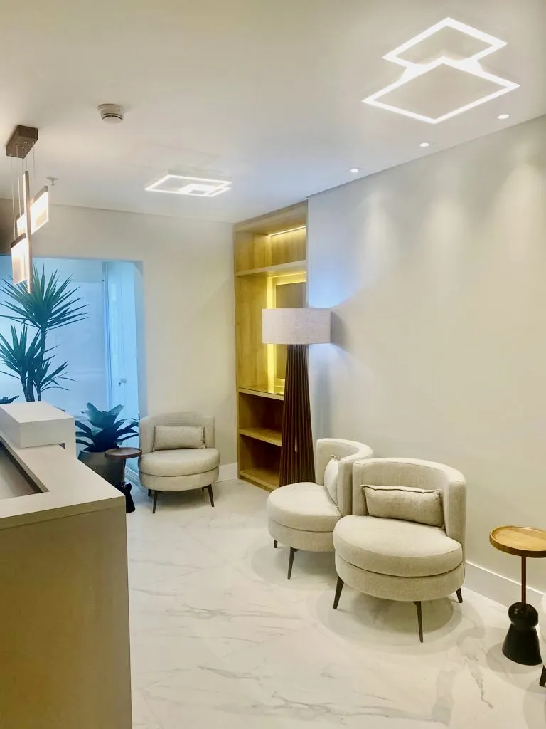 Sala de espera com poltronas e marcenaria iluminada